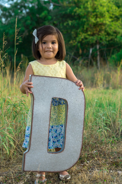 Little girl holding big letter D