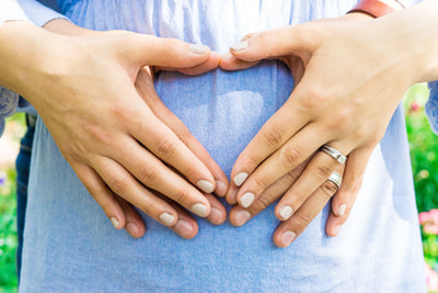 close up of couple's hands on belly