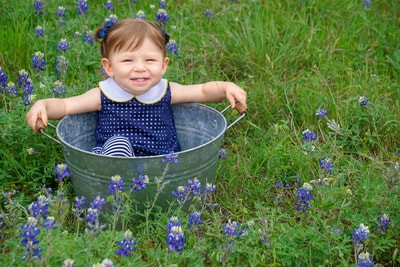 Isa in bucket with bluebonnets smiling